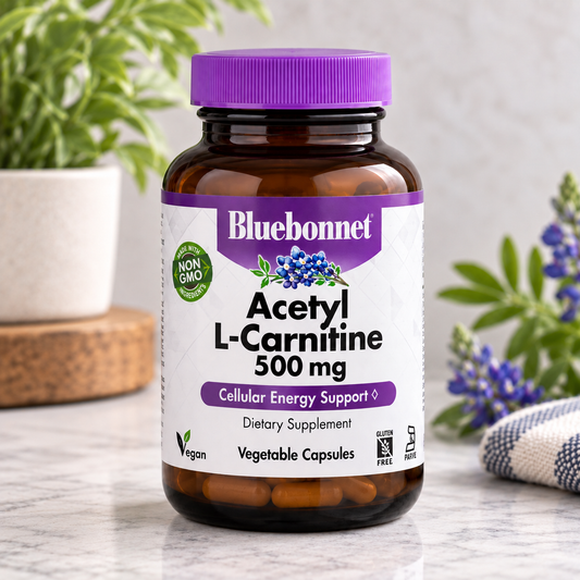 A bottle of Bluebonnet Acetyl L-Carnitine 500 mg dietary supplement, featuring an amber glass bottle with a purple cap and a white label with purple and green accents, set on a marble surface with blurred plants in the background.
