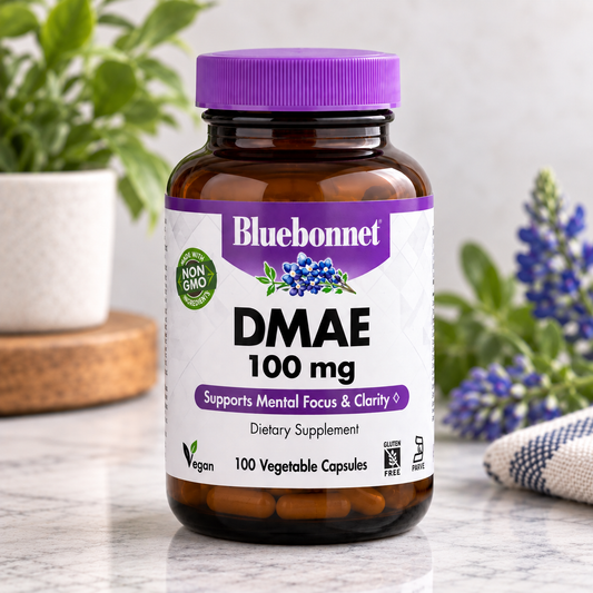 Bluebonnet DMAE 100 mg dietary supplement bottle with a purple cap, set on a marble surface with blurred plants and flowers in the background.