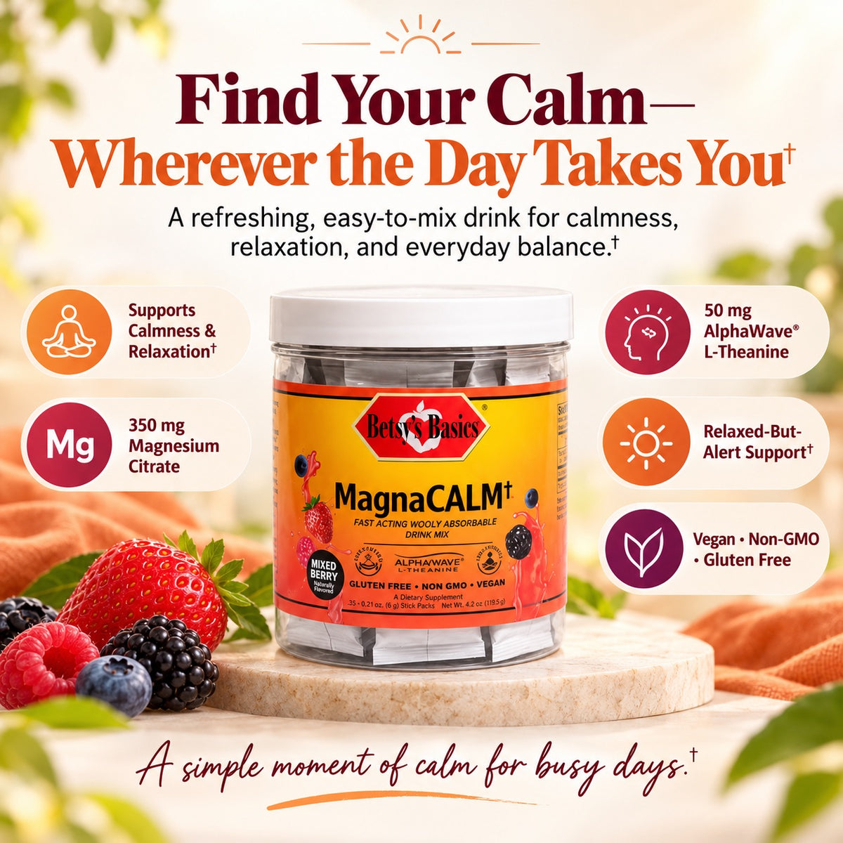 A jar of Hey! Basics MagnaCALM liquid supplement centered on a light wood surface, surrounded by fresh berries and orange fabric, with marketing text and icons about magnesium, alpha-wave support, and vegan/non-GMO qualities.