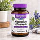 A bottle of Bluebonnet Magnesium L-Threonate dietary supplement capsules, set on a marble surface with blurred potted plants and flowers in the background.