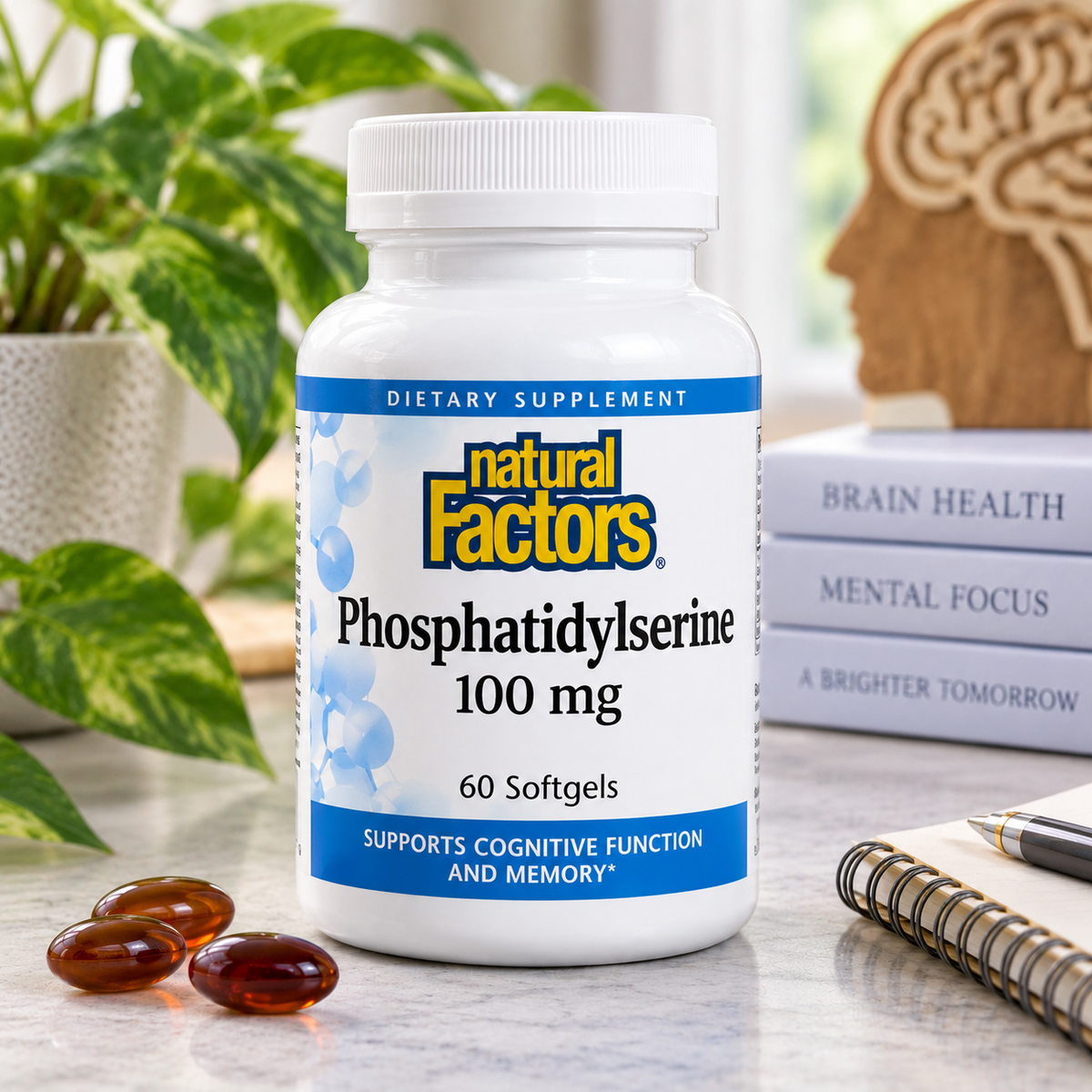 A bottle of Natural Factors Phosphatidylserine 100 mg dietary supplement, 60 softgels, displayed on a marble desk with a green plant, books, and softgels in the foreground.