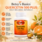 Betsy's Basics Quercetin 500 Plus dietary supplement bottle shown on a warm beige background with orange slices, white flowers, and text highlighting benefits such as antioxidant support and immune function.