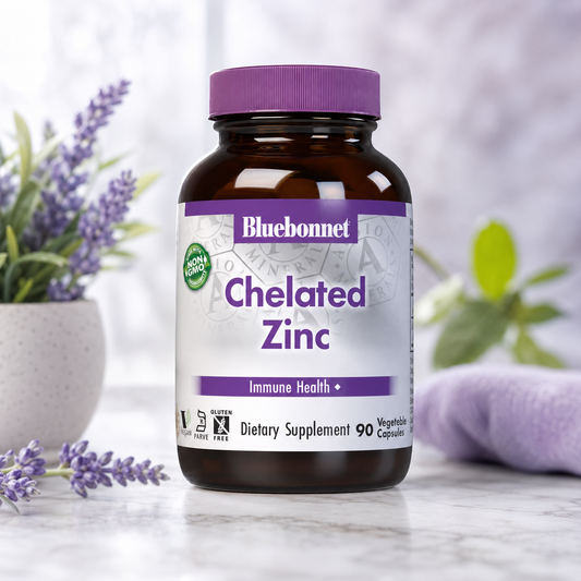 A bottle of Bluebonnet Chelated Zinc dietary supplement, featuring an amber glass bottle and a purple cap, set on a marble surface with lavender flowers and a soft-focus background.